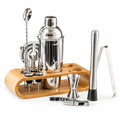 17-piece RüK stainless steel cocktail shaker set with bamboo stand, including shaker, jigger, muddler, bar spoon, strainer, pourers, fruit picks, and corkscrew, displayed on white background with realistic shadows, professional studio lighting.
