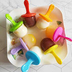 Homemade mini popsicles frozen in silicone mold with colorful handles