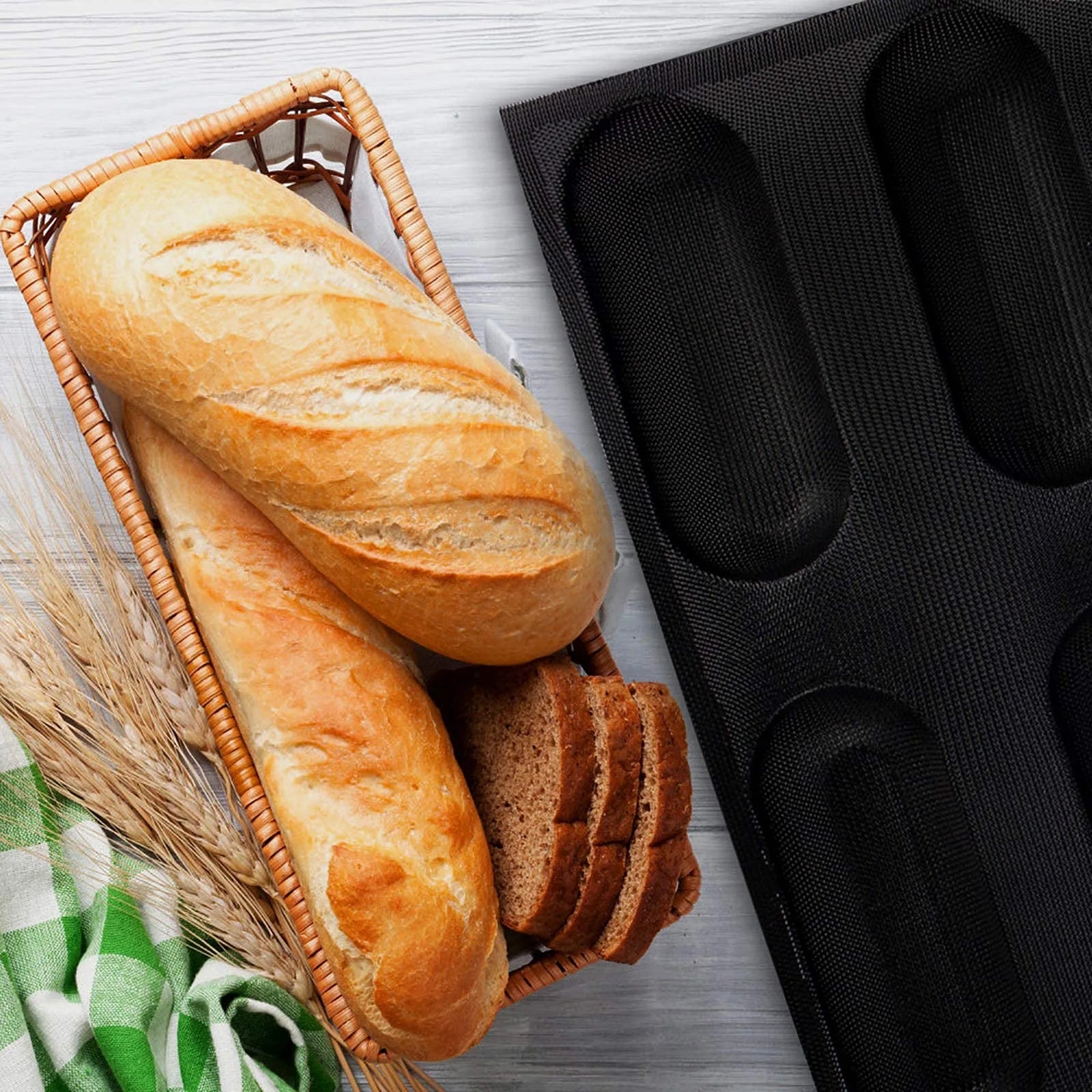 Black silicone bread mold beside fresh baguettes and homemade bread for baking use