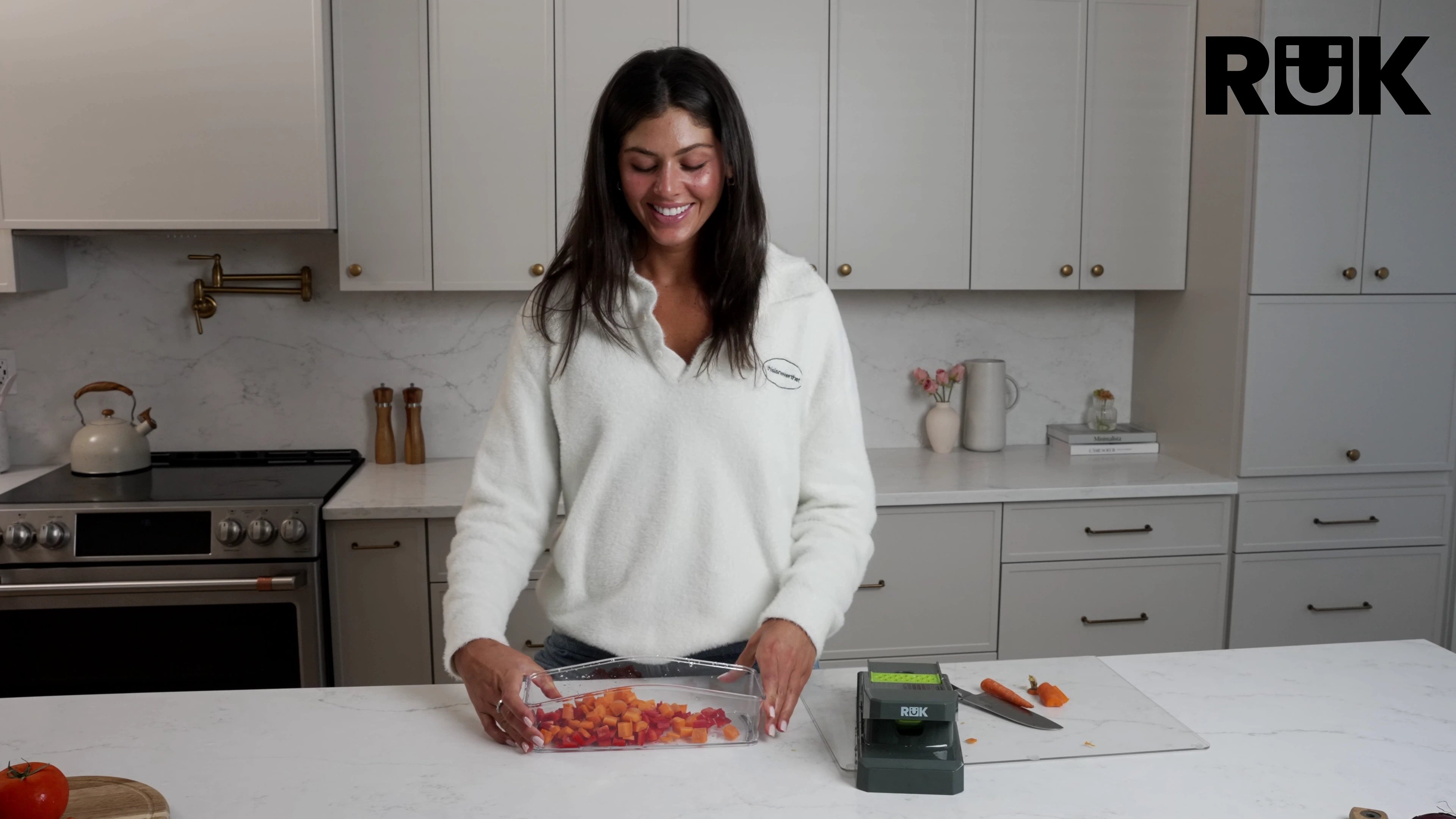 Woman preparing diced vegetables with the RüK 10-in-1 vegetable chopper in a modern kitchen.